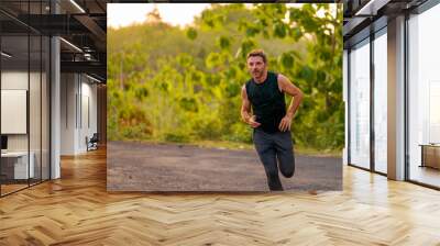 lifestyle portrait of young attractive and healthy man on his 30s or 40s running on country road doing jogging workout training happy on beautiful natural background Wall mural