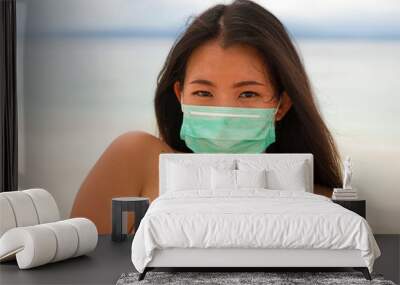 use of medical face mask in public places- young attractive Asian Chinese woman enjoying beach holidays in bikini and protective facial mask in prevention vs virus infection Wall mural