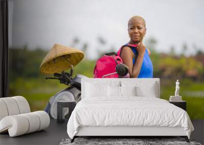 young beautiful and happy tourist african american black woman looking around with scooter motorbike at green field tropical landscape in adventure trip and summer holidays travel concept Wall mural