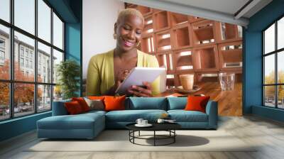 young elegant and beautiful black African American business woman working online with digital tablet pad at coffee shop smiling happy Wall mural