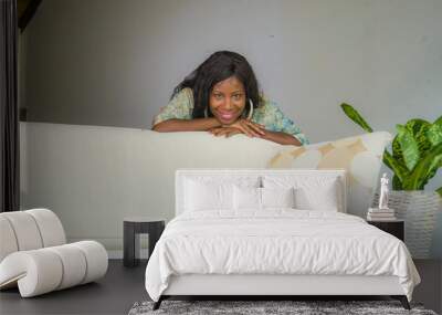 young stylish beautiful and happy black African American woman posing at living room sofa couch in her modern apartment smiling cheerful and relaxed Wall mural