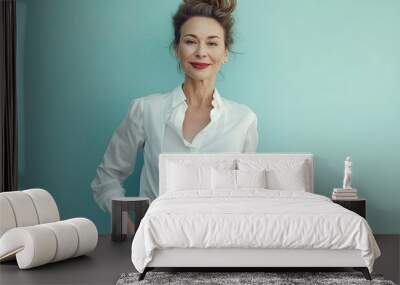 a middle-aged, elegant businesswoman stands in front of a blue wall, looking happy with her hands in Wall mural