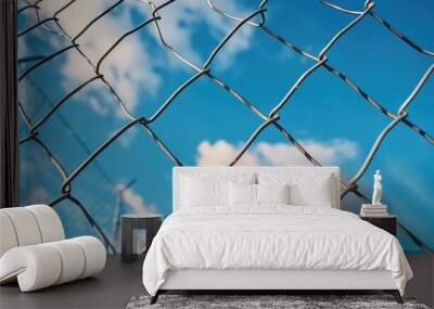 Close up view of a modern iron wire fence against a blue sky Wall mural