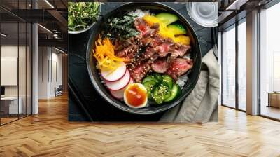 Components for a mouthwatering rice bowl featuring tender beef strips, yellow radish, cucumber, seaweed, pickles, and bonito flakes, set on a table adorned with cutlery, a clear glass, and a Wall mural