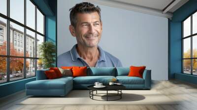 Middle aged attractive man in a casual polo shirt poses confidently with a relaxed expression and a genuine smile looking to the side Wall mural