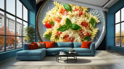 Pasta radiatori topped with grated cheese, basil, and tomatoes, presented from a top view on a plate with cutlery, suitable for lunch. Wall mural