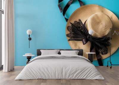 Straw hat with black ribbon and fan from above on blue background Wall mural