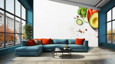 Top view of a white background showcasing a bowl filled with a variety of fresh raw vegetables including cabbage carrot zucchini lettuce watercress salad cherry tomatoes avocado nuts and po Wall mural