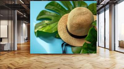 Woman s hat and green leaf on blue background suggesting seaside leisure Wall mural