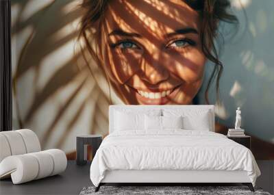 Smiling woman with palm leaf shadows on face, portrait Wall mural