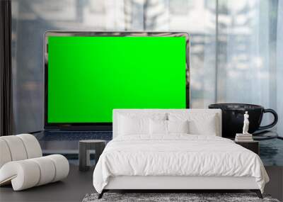 Mockup of laptop computer with empty screen with coffee cup and smartphone on table of the coffee shop outdoor background,Green screen Wall mural