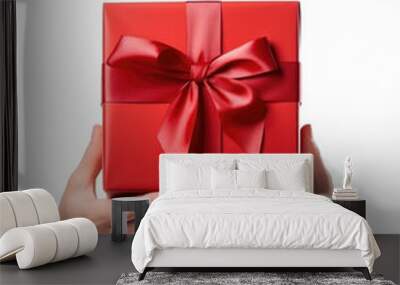 Two hands holding a red gift box with a bow isolated on a white background Wall mural