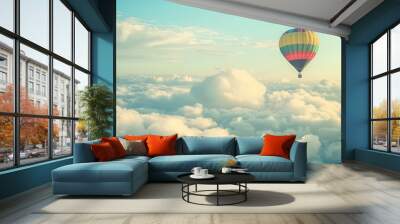 A hot air balloon floats among fluffy clouds, the vibrant colors of the balloon contrasting with the soft white of the clouds. Wall mural