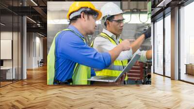 A skilled mechanic in a metal lathe is checking parts on a laptop computer. Engineers are working and repairing machines in industrial. Wall mural