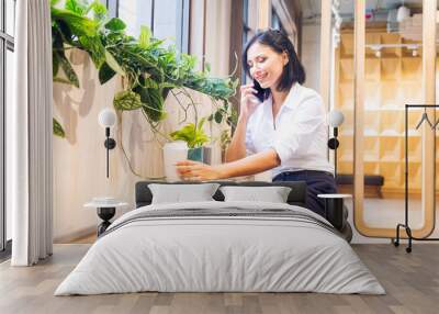 Co working space concept. A young woman is working in a common area. Women are using mobile phones to contact work. Wall mural