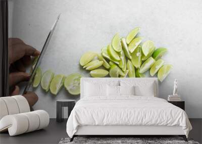 Overhead view of limes being sliced into wedges, top view of hand slicing green limes, process of making lime cheong and cocktails Wall mural