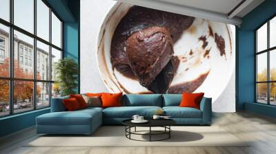 Thick chocolate madeleine batter that has rested in a white bowl, thick chocolate cake batter, brownie batter on a silicone spatula Wall mural