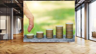 man finger walking on coins stack on wood table in park with sunrise. business budgeting financial banking saving and startup concept success increase growing investment. Wall mural