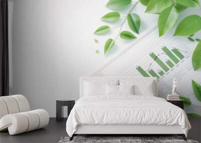 An eco-friendly financial report with green data charts is artistically displayed alongside fresh leaves on a pristine white background. The ample copy space emphasizes the concept of sustainable Wall mural