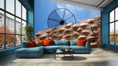 broken satellite dish on rock brown building with bright blue sky Wall mural