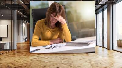 Desperate businesswoman with hand on forehead, light effect Wall mural