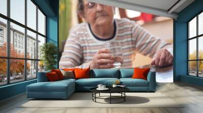 Elderly woman holding a glass of water Wall mural