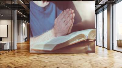 Man praying with his hands over the bible Wall mural