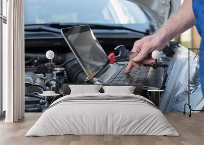 Mechanic using laptop for checking car engine Wall mural