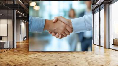 A close-up of two business professionals shaking hands, representing agreement, trust, and collaboration. Wall mural