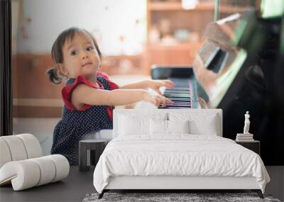 Little Asian cute girl playing piano Wall mural