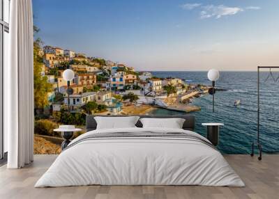 Beautiful colorful purple greek sunset sunrise coast view to a small greek town village with harbour fishing boats blue sea with crystal clear water, Ikaria Island, Armenisits, Sporades, Greece Wall mural