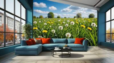 Beautiful bright natural image of fresh grass spring meadow with dandelions with blurred background and blue sky with clouds Wall mural