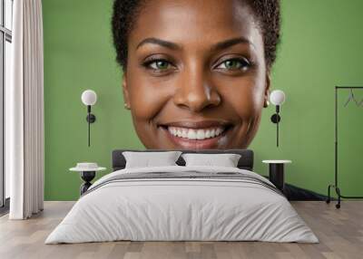 Full framed very close face portrait of a smiling 40s black woman with green eyes looking at the camera, studio shot,green background. Wall mural