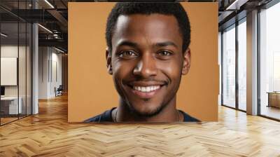 Full framed very close face portrait of a smiling young black man with amber eyes looking at the camera, studio shot,amber background. Wall mural