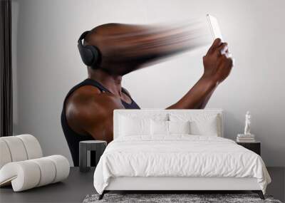 African man athlete on a light background uses a smartphone. The man's face is transferred, sucked, absorbed into the phone. Concept of social network dependency, phone addiction. Wall mural