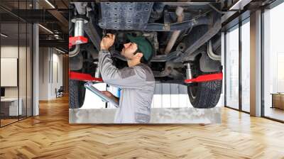 Mechanic vehicle service checking under car in garage. Wall mural