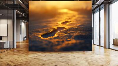 A close-up of two footprints in the sand, bathed in golden sunlight at sunset. Wall mural