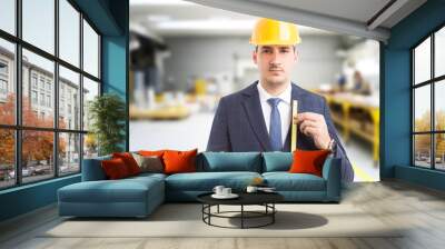 Engineer holding measure tape in factory. Wall mural