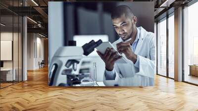 Announcing his findings to the world. Shot of a scientist recording his findings on a digital tablet. Wall mural