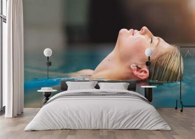 Cool the body, calm the mind. Shot of a young woman relaxing in the pool at a spa. Wall mural