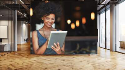 Customers have left some great reviews online about her cafe. Cropped shot of a young woman using a digital tablet in a cafe. Wall mural