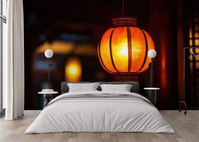 A glowing orange lantern hanging in a dark room, casting warm light and shadows around. Wall mural