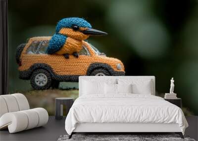 A small crocheted kingfisher sits in a crocheted car, perched on a log. Wall mural