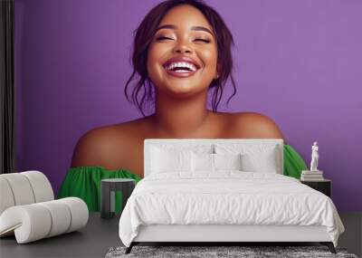 Portrait of a beautiful black woman with curly hair smiling against a purple background wearing a green off-the-shoulder top. Wall mural