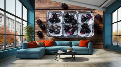 Fresh juicy blackberry and ice cubes on brown wood background. Flat lay, top view. Summer freshness, poster design.  Wall mural