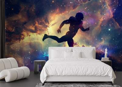 Silhouetted American football player leaping in dynamic motion against a backdrop of swirling galaxies and nebulae vibrant colors contrast between dark silhouette and bright cosmic background epic spo Wall mural