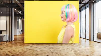 Beautiful woman in a bright colorful wig on a split yellow and pink background Wall mural