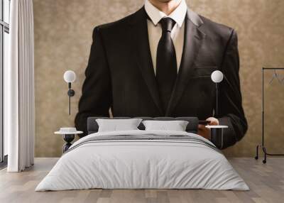 Businessman holding a tablet computer on a dark vintage background Wall mural