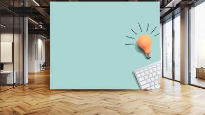 Computer keyboard with a yellow light bulb from above Wall mural