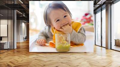 Happy little baby boy eating food in his house Wall mural